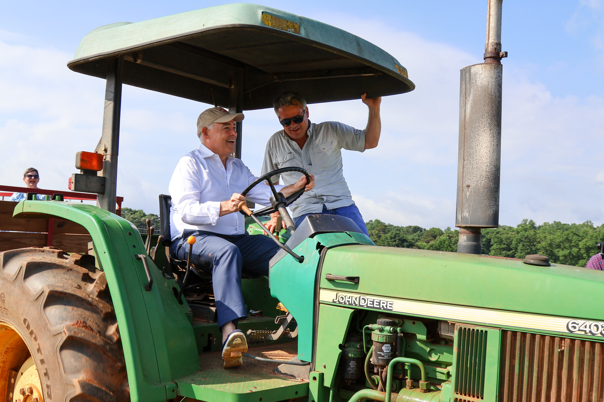 President Cabrera driving a tractor with Drew Echols, co-owner of Jaemor Farms.