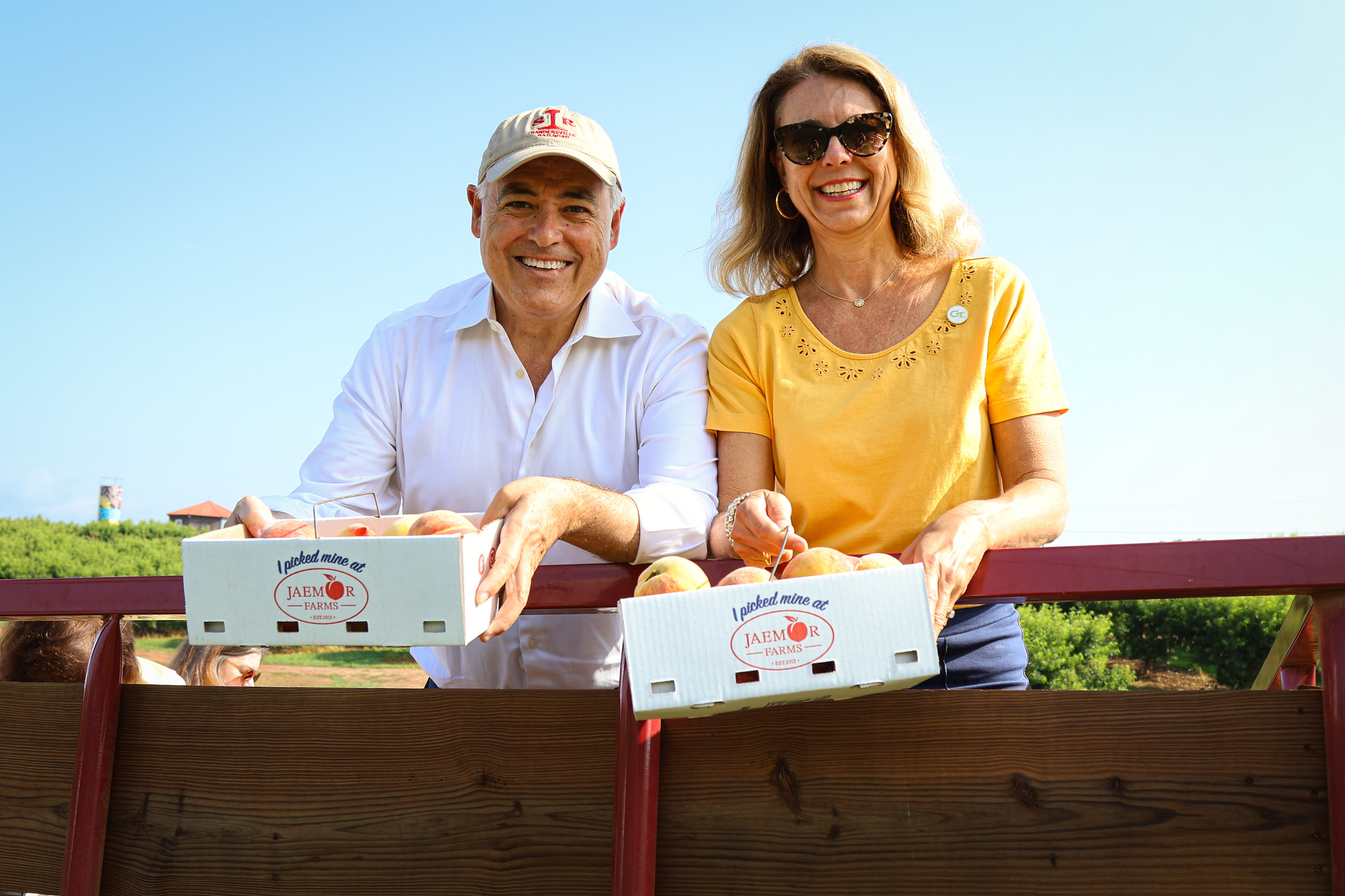 President Cabrera and Dr. Beth Cabrera holding boxes of handpicked peaches at Jaemor Farms.